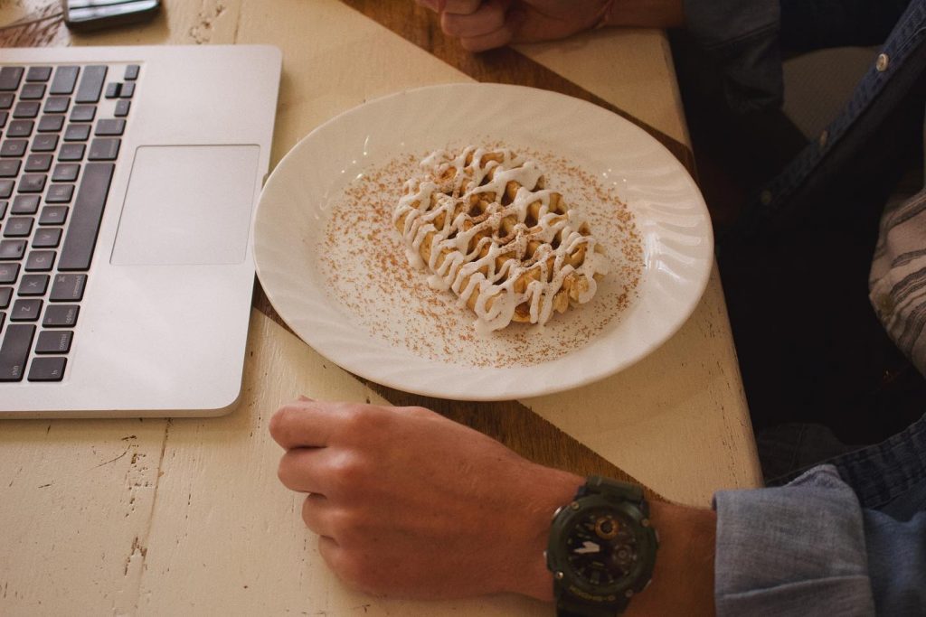 cinnamon roll liege waffle on plate in front of laptop