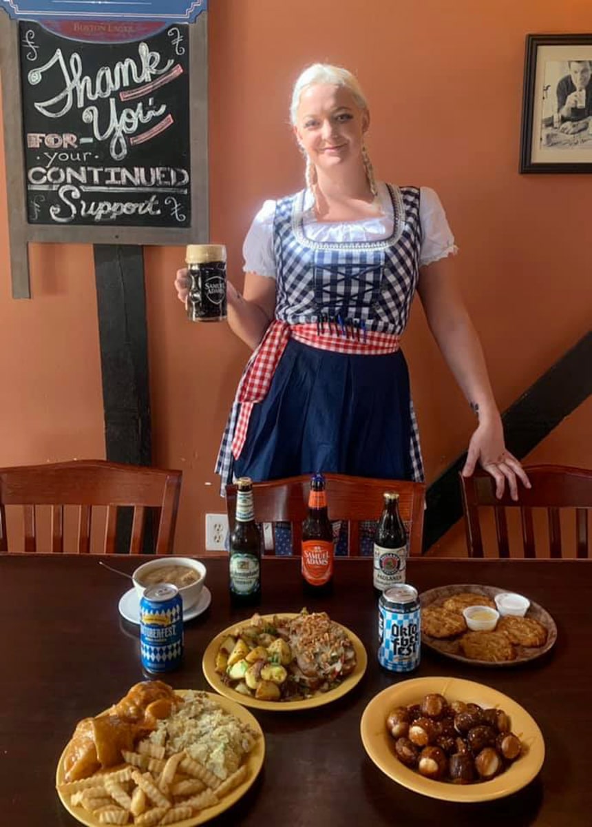 Woman server holding german beer with german entrees at Freibergs restaurant