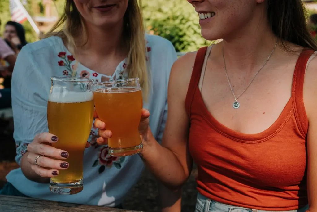 two women cheering beers together at a brewery