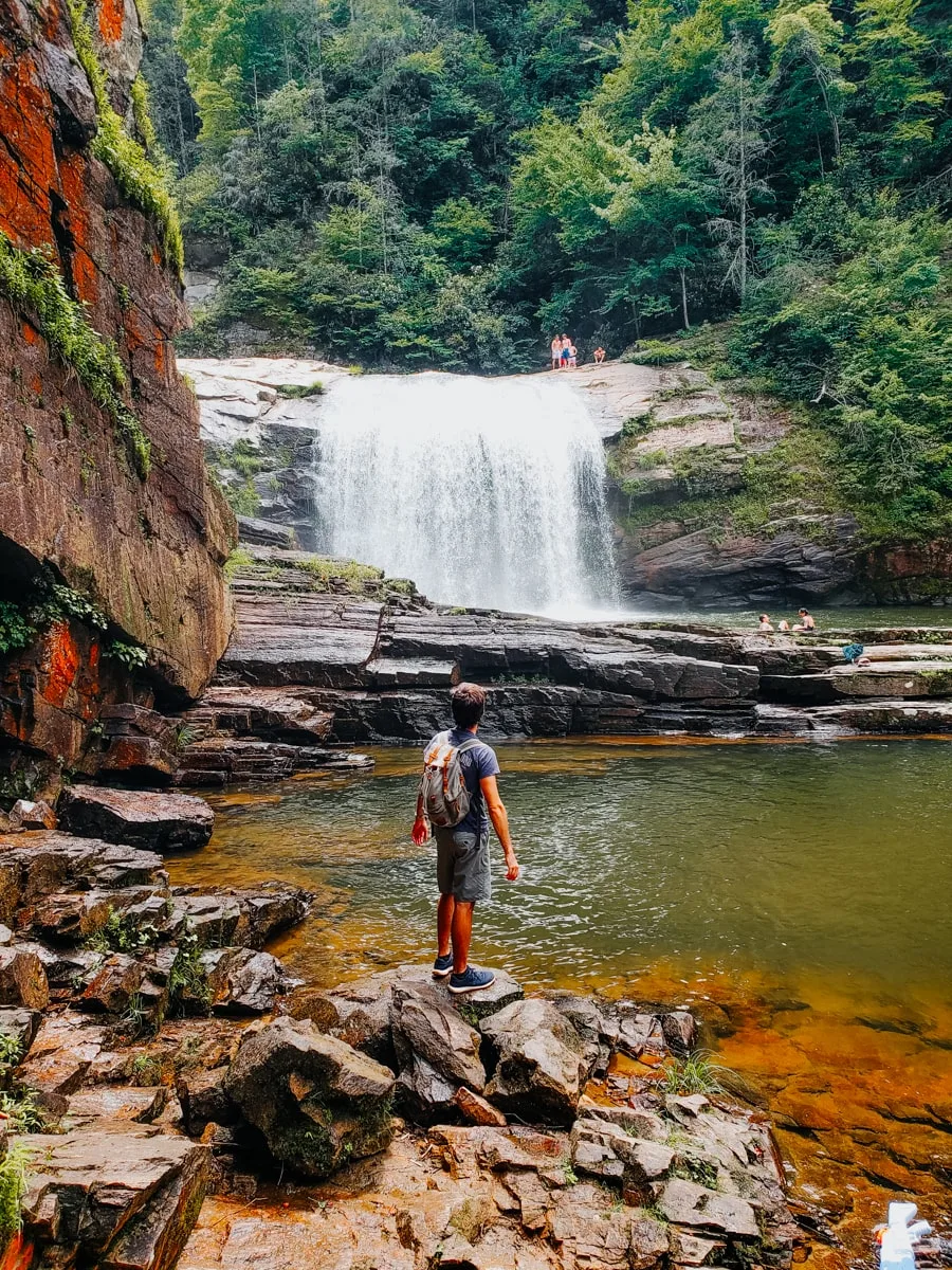 Hiker stands on rock with Compression Falls in the background