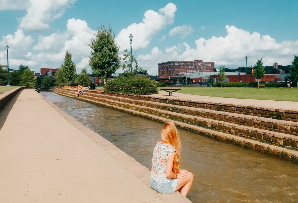 Girl sitting beside creek in Founder's Park in Downtown Johnson City, TN