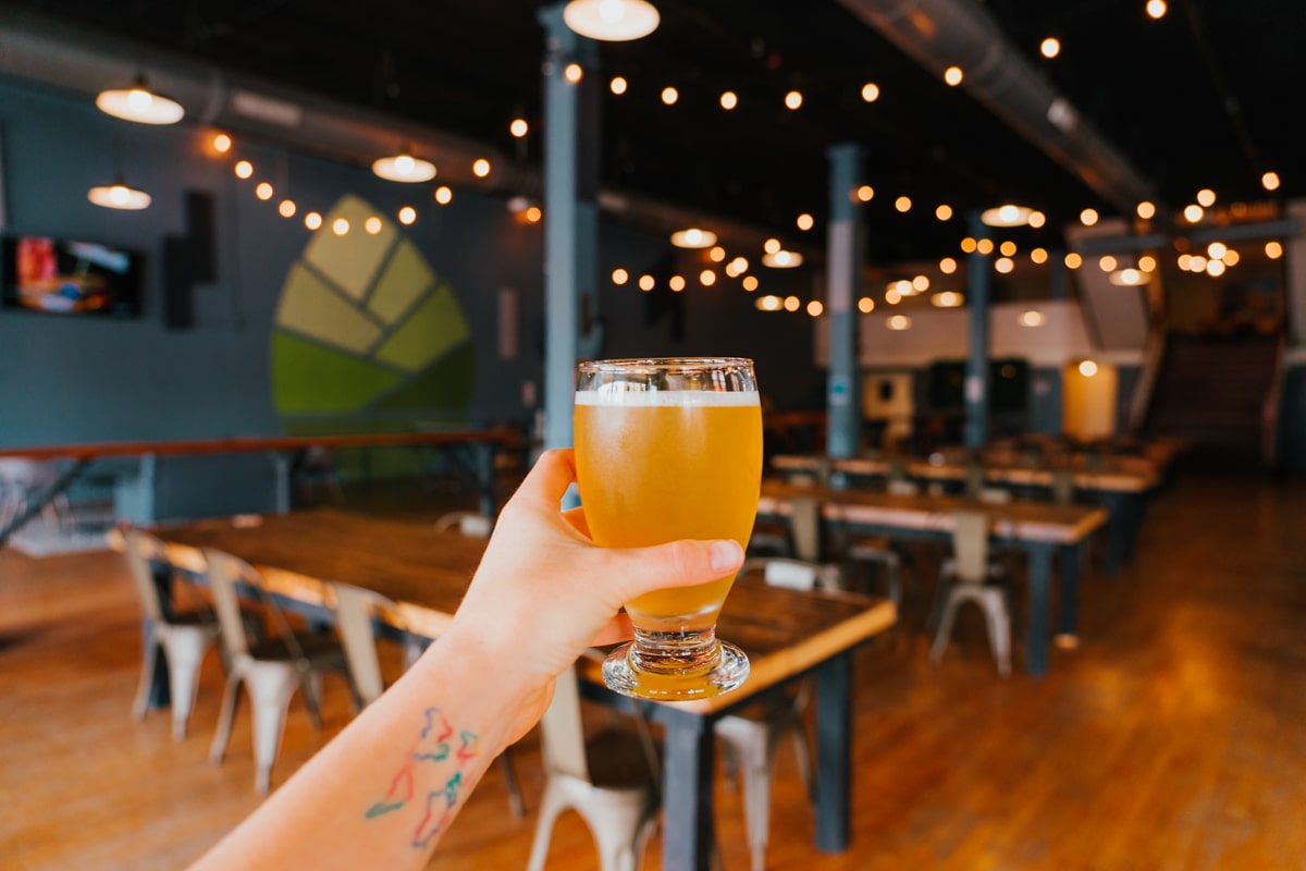 Woman holding 10 oz. beer inside State Street Brewing Co.