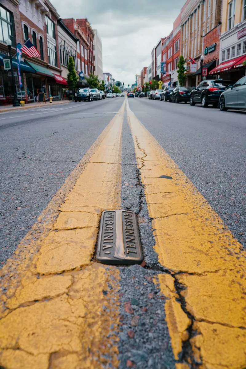 Painted yellow lines on State Street with plaque indicating the border line between Bristol, Tennessee and Bristol, Virginia.