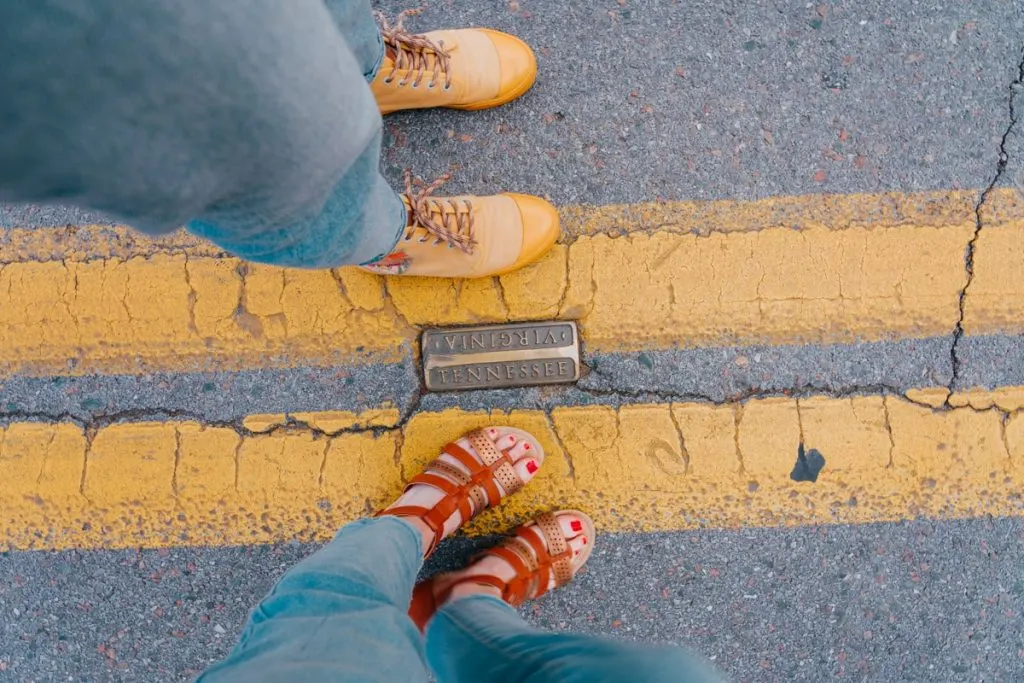 Two girls standing on each side of the Bristol TN-VA border, wearing yellow adventures shoes and open sandals.