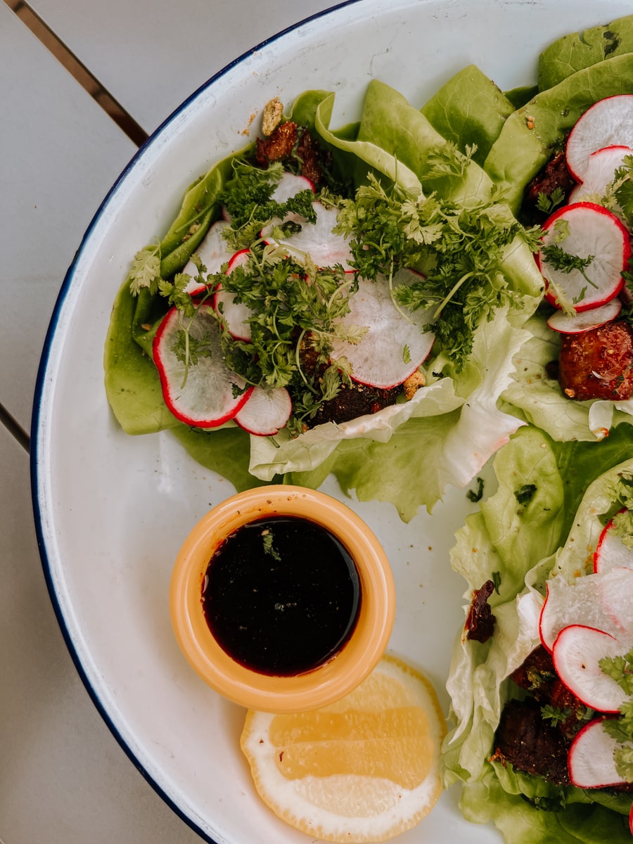 Beef lettuce wraps on white plate with side of sauce at Timber! restaurant.