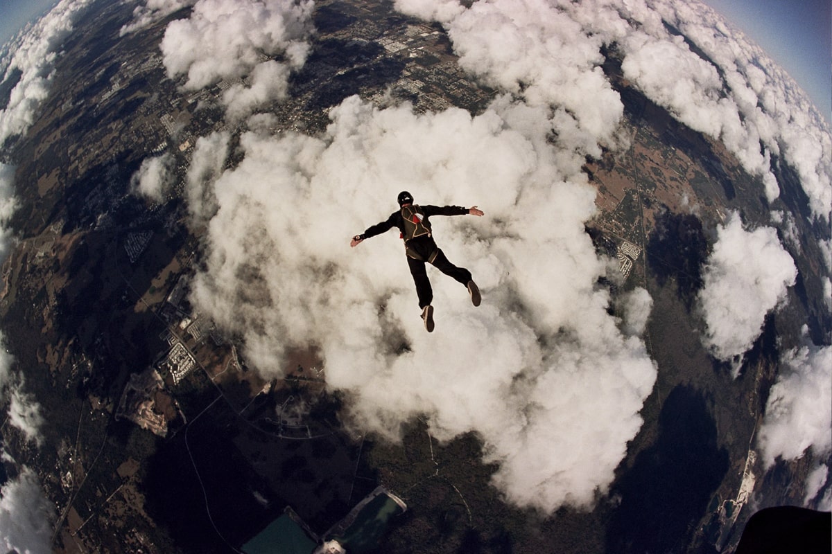 Man jumping out of plane skydiving above the clouds 