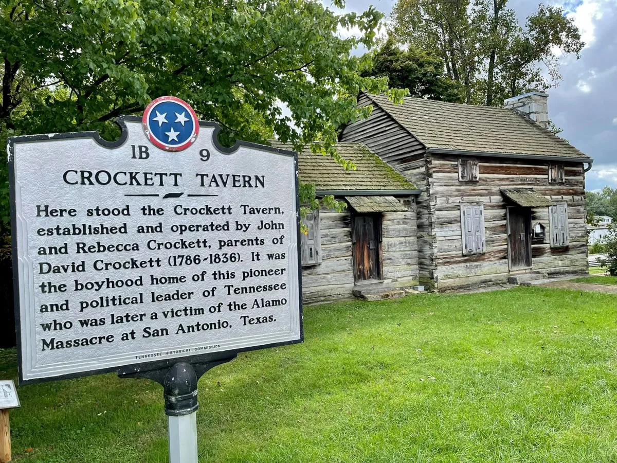 Crockett Tavern Museum with sign and house in the background