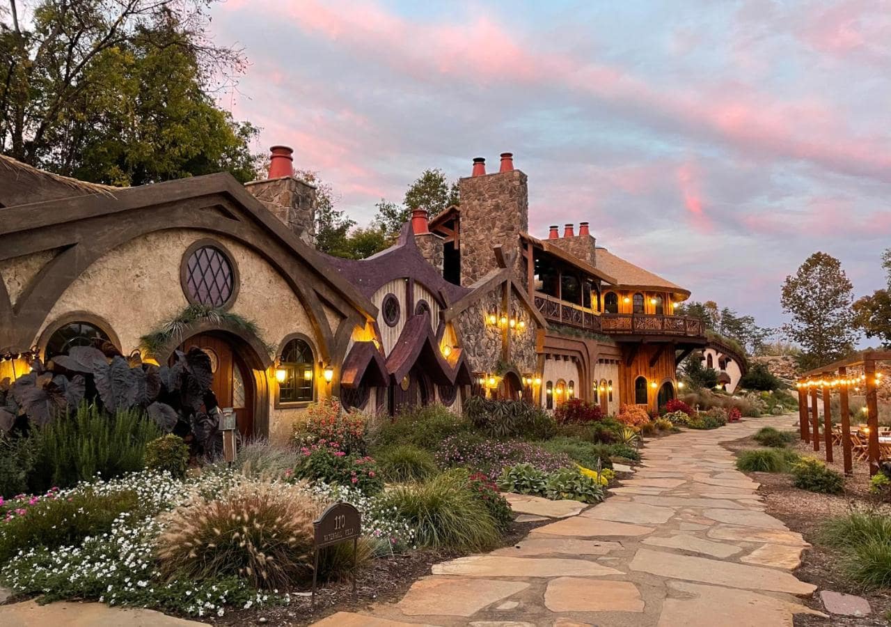 Exterior of the Ancient Lore Village with rocked pathway, flowers, and twinkling lights.