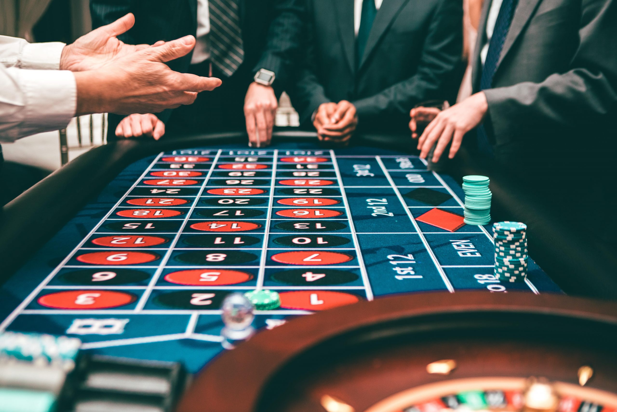 gamblers standing around a roulette table placing bets