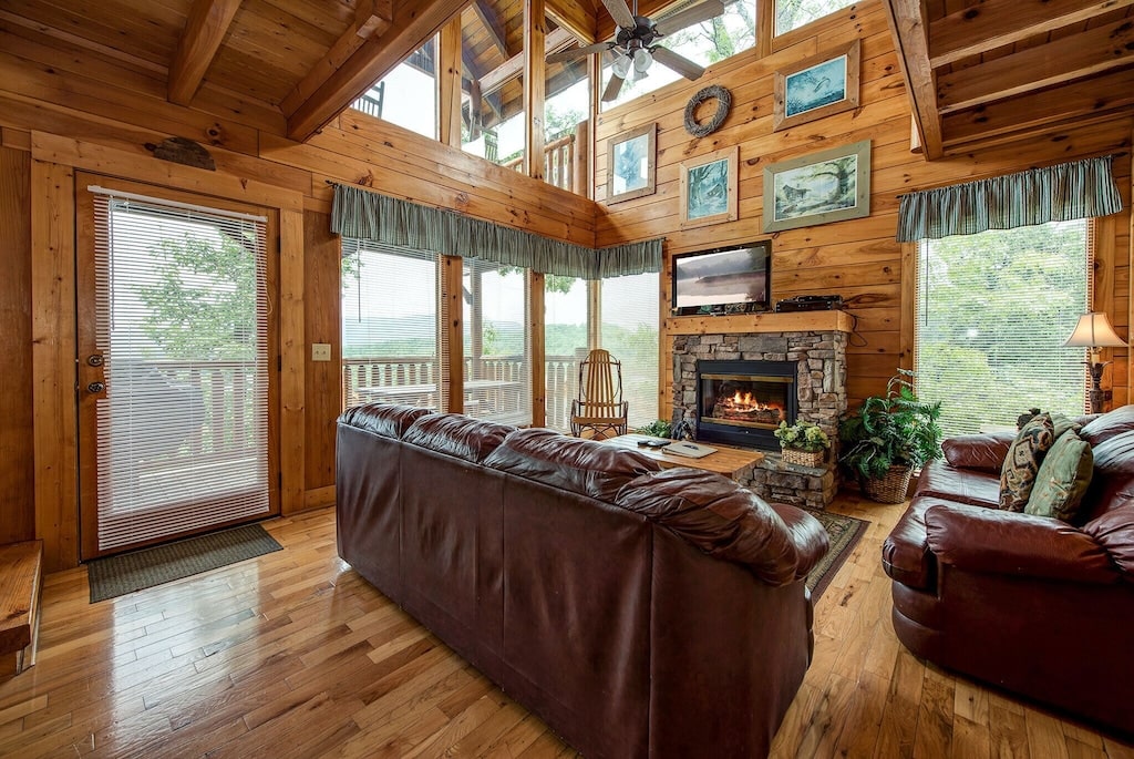 floor to ceiling windows inside the living room of a cabin rental with a fireplace