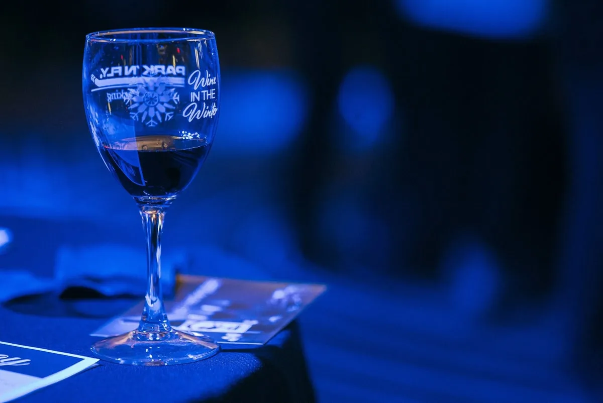 a wine glass with Wine in the Winter etch with a blue background