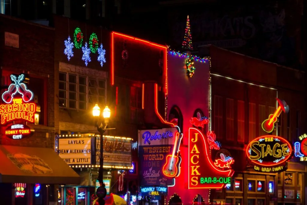 Downtown Nashville in the winter with neon lights illuminating restaurants and street.