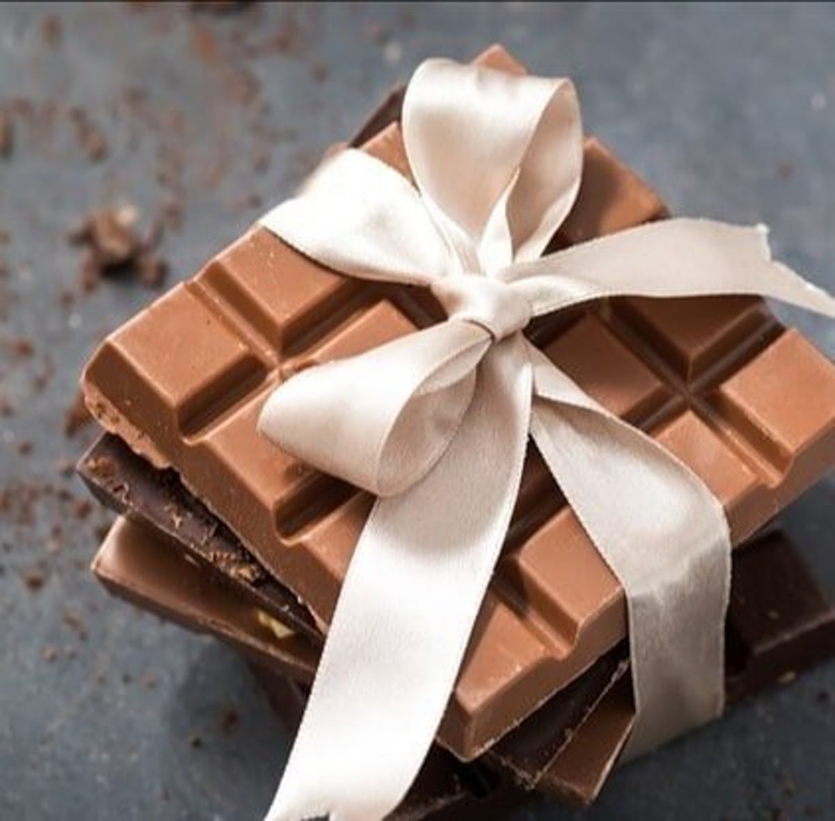 A wrapped gift of chocolate bars with a white silk bow