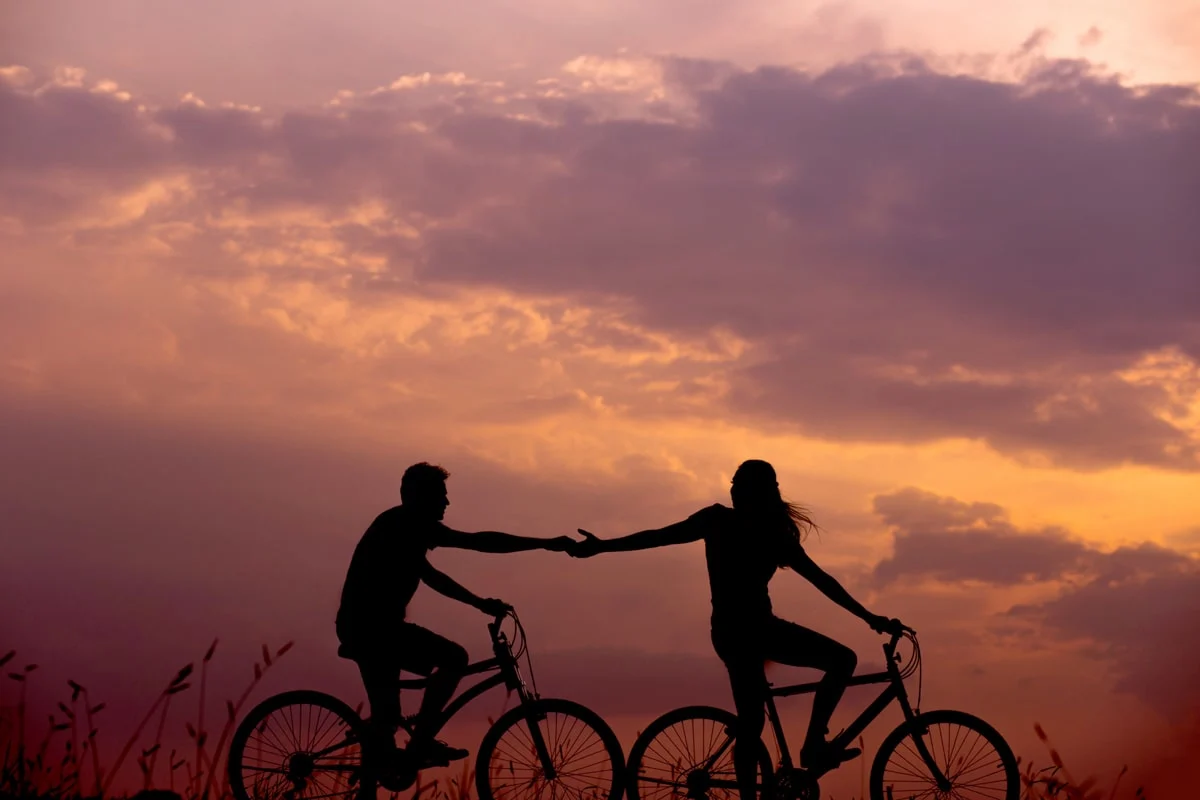 people riding bikes while holding hands during sunset