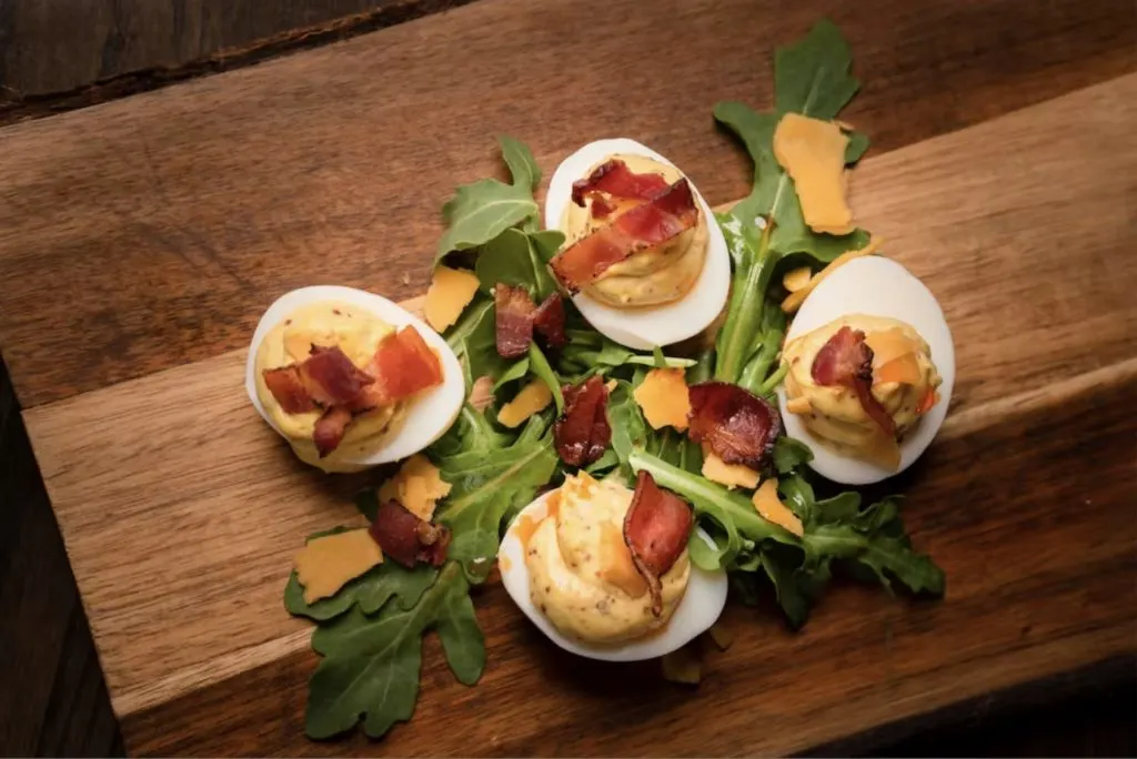 Fancy deviled eggs appetizer from Vivian's Table restaurant on wooden butcher's block.