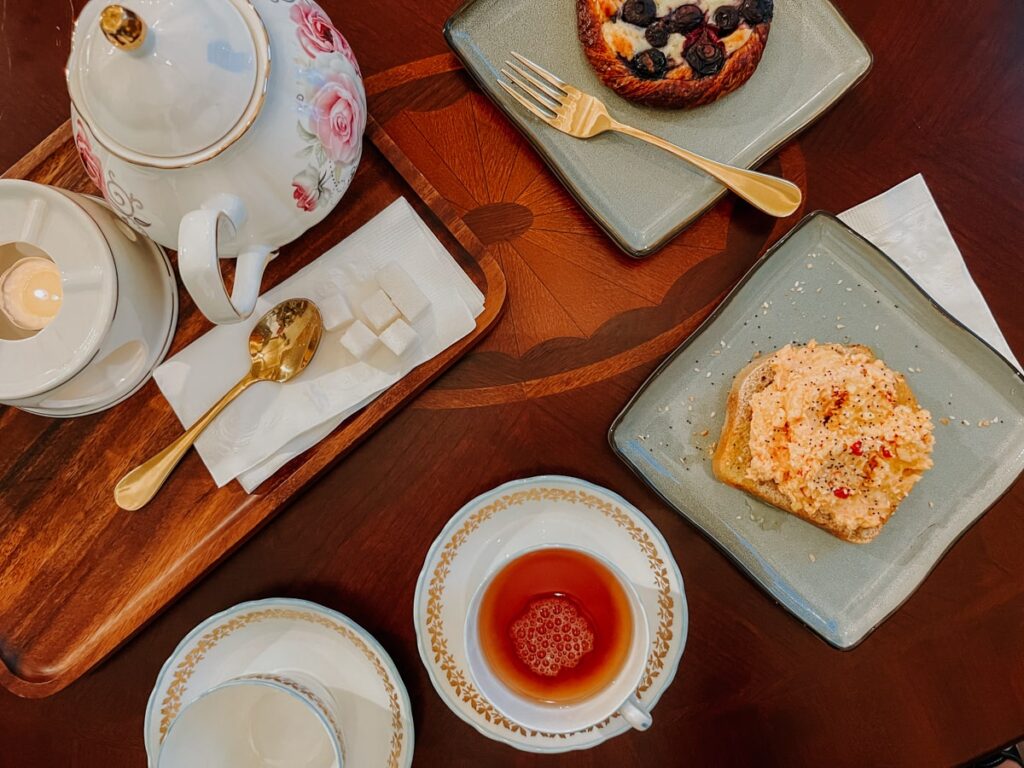 Top-down view of table with teapot, tea cups, and plates of pastries and toast.