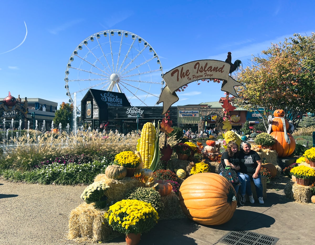 People posing in front of the Great Smoky Mountain Wheel and Ole Smoky Mountain Distillery at the Island in Pigeon Forge TN 