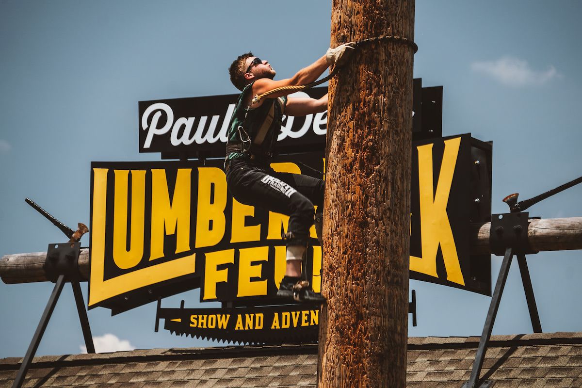 man climbing up pole at the paula deens lumberjack feud show