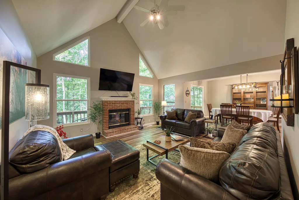 Inside a modern vacation rental in Knoxville with fireplace, smart TV, full dining room, and couches.