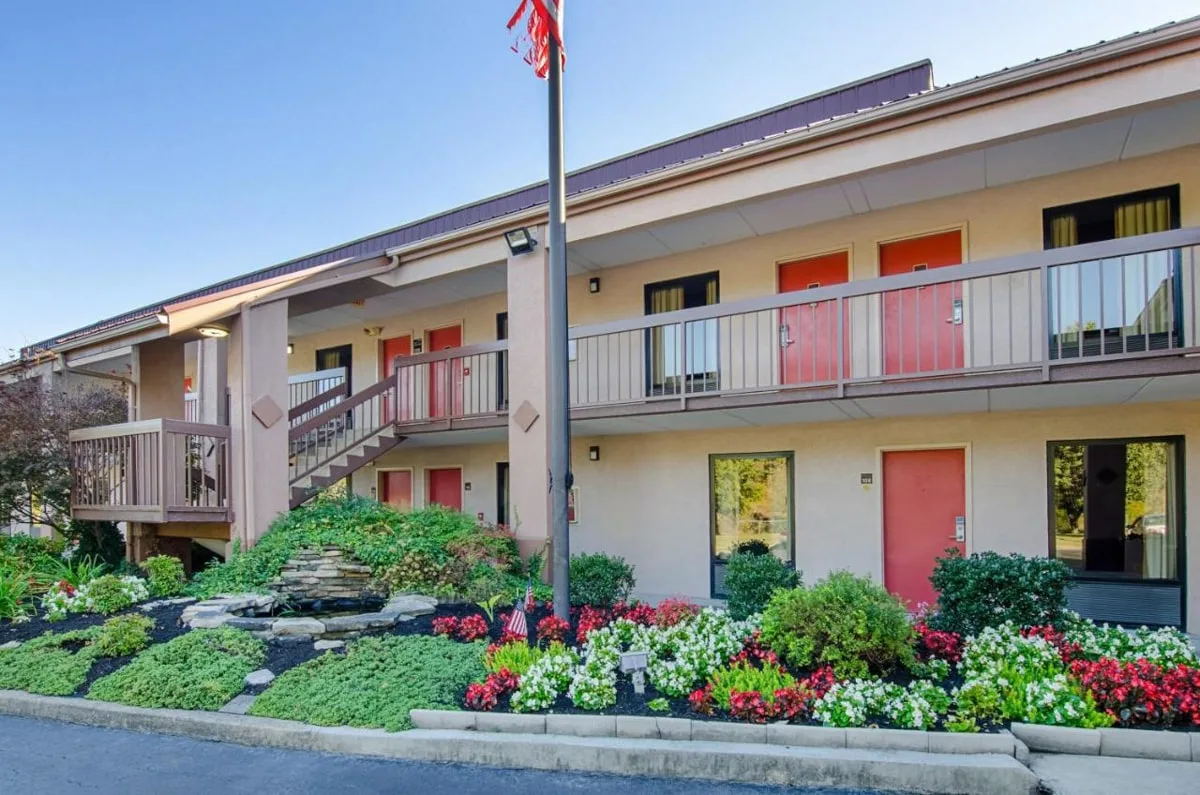 Red Roof Inn exterior with red doors and pretty landscaping with flowers