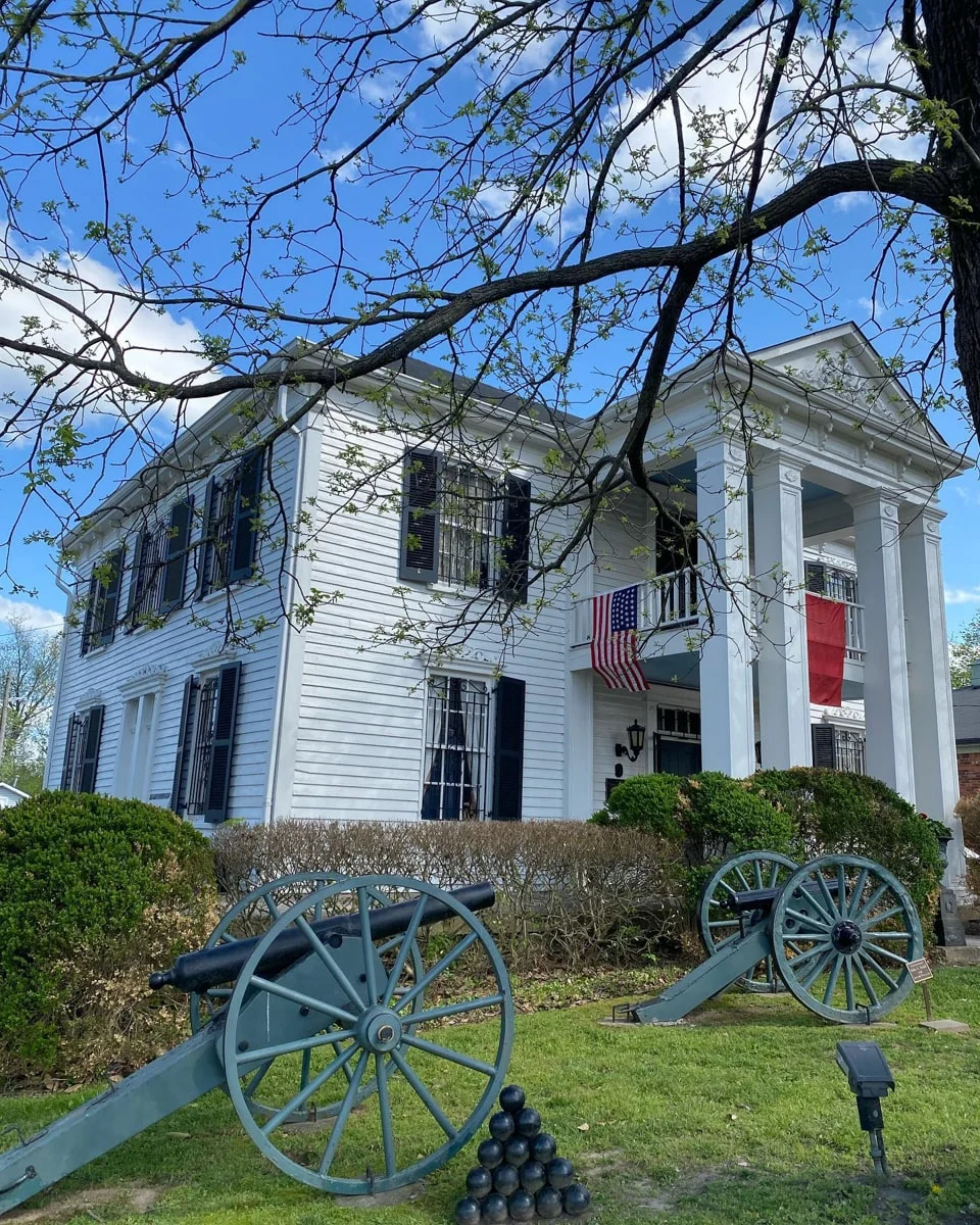 The Lotz House with a tree and flags hanging from porch 