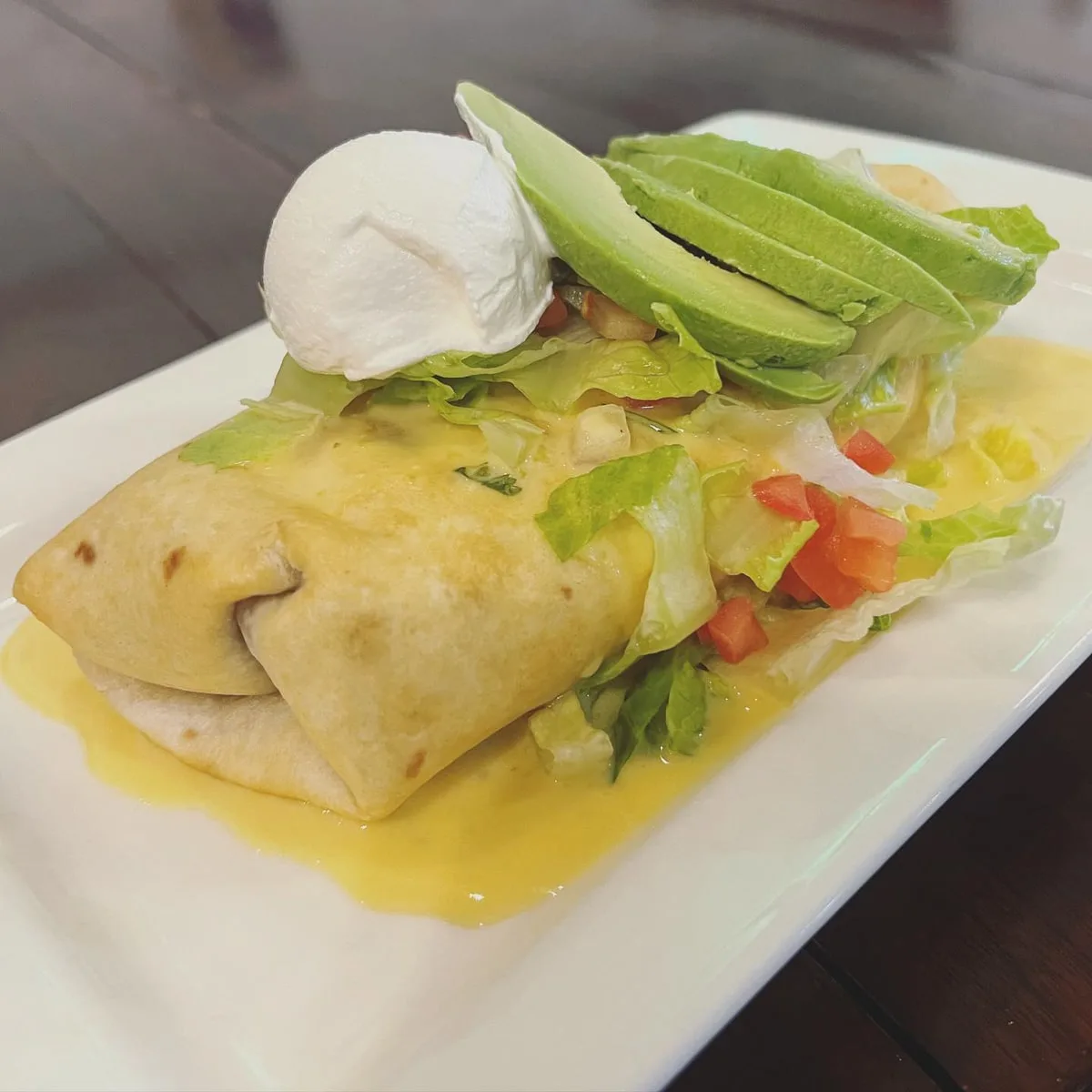 A fried chimichanga topped with fresh avocado, pico de gallo, and sour cream at Texas Burritos & more in jonesborough TN