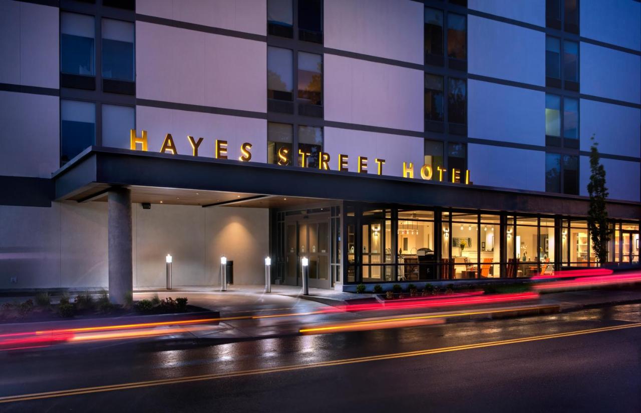 Hayes street hotel exterior with sign and blurred lines of cars driving in front at night 
