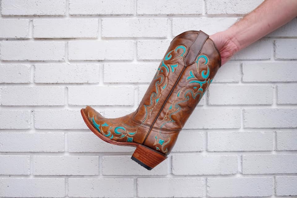 a person holding a cowboy boot with teal coloring