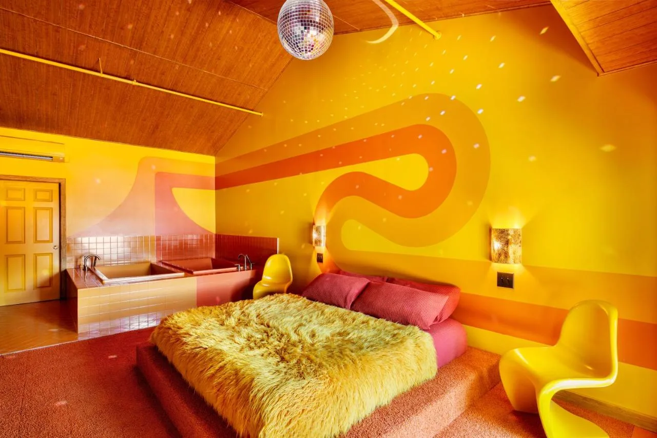 groovy motel room with orange and yellow wall, shag carpeting, bathtub, and shag bed comforter at the dive motel in nashville tn 