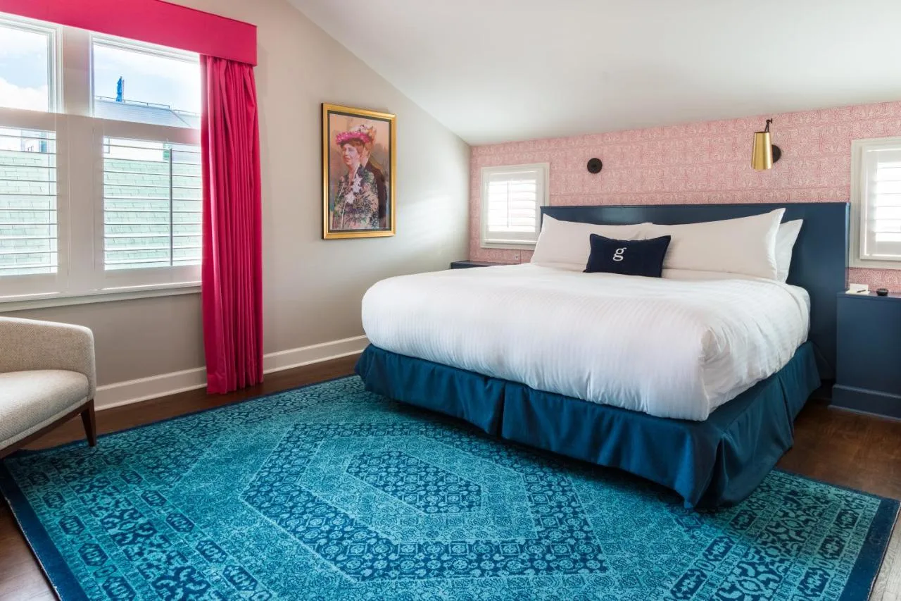 plush bed with custom pink wallpaper and a blue thick rug at the Germantown inn in nashville tn 