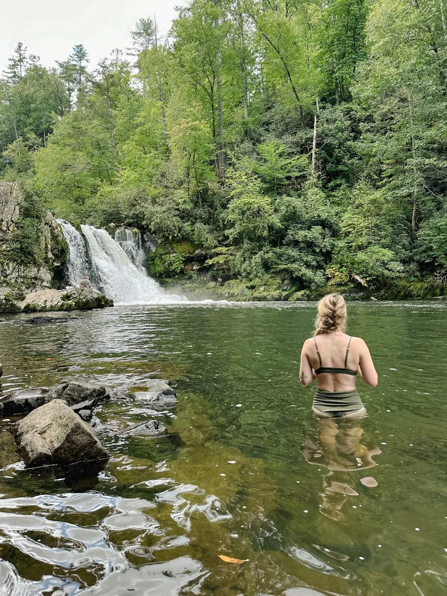 woman cooling off at abrams falls with waterfall in background in cades cove tennessee
