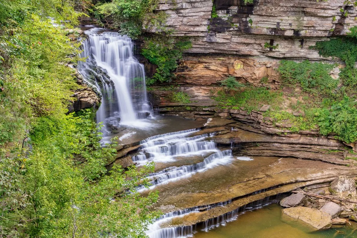 top view of cummins falls with green trees and tiers of water flowing over rocks 