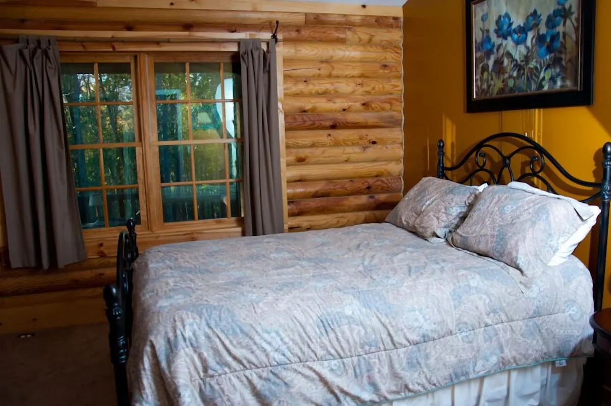 log cabin with queen sized bed and window looking into the woods in murfreesboro tn 