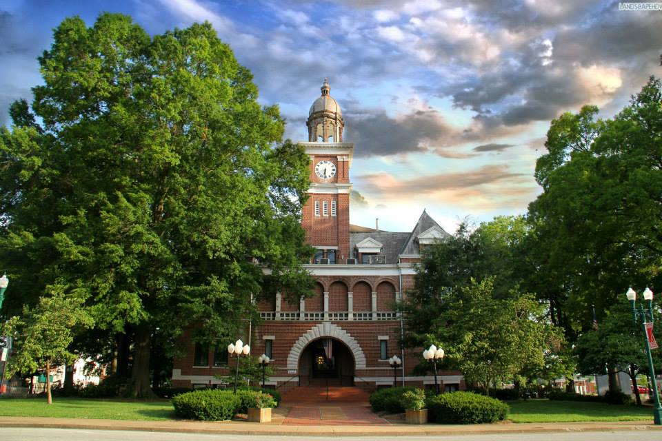 brick clock tower building in downtown paris tn surrounded by large trees  