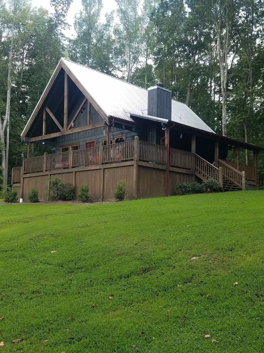 exterior cabin view with gray wooden siding, wrap around porch, and grassed front yard in murfreesboro tn 