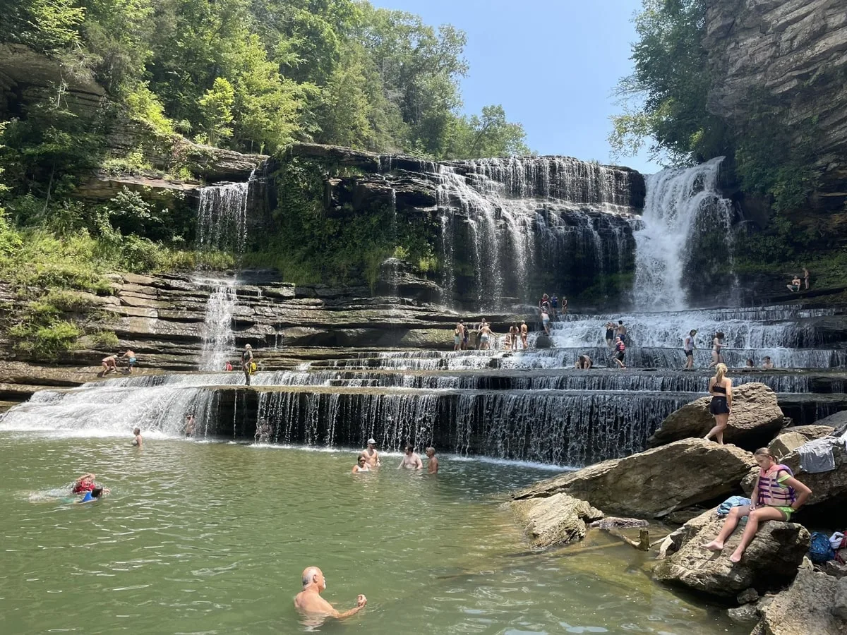 people swimming at cummins falls state park with the waterfall in the background