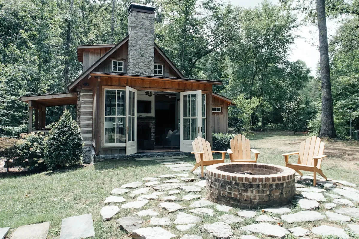 cute cabin with chimney and open doors with firepit and chairs as a cozy cabin stay near cookeville tn 