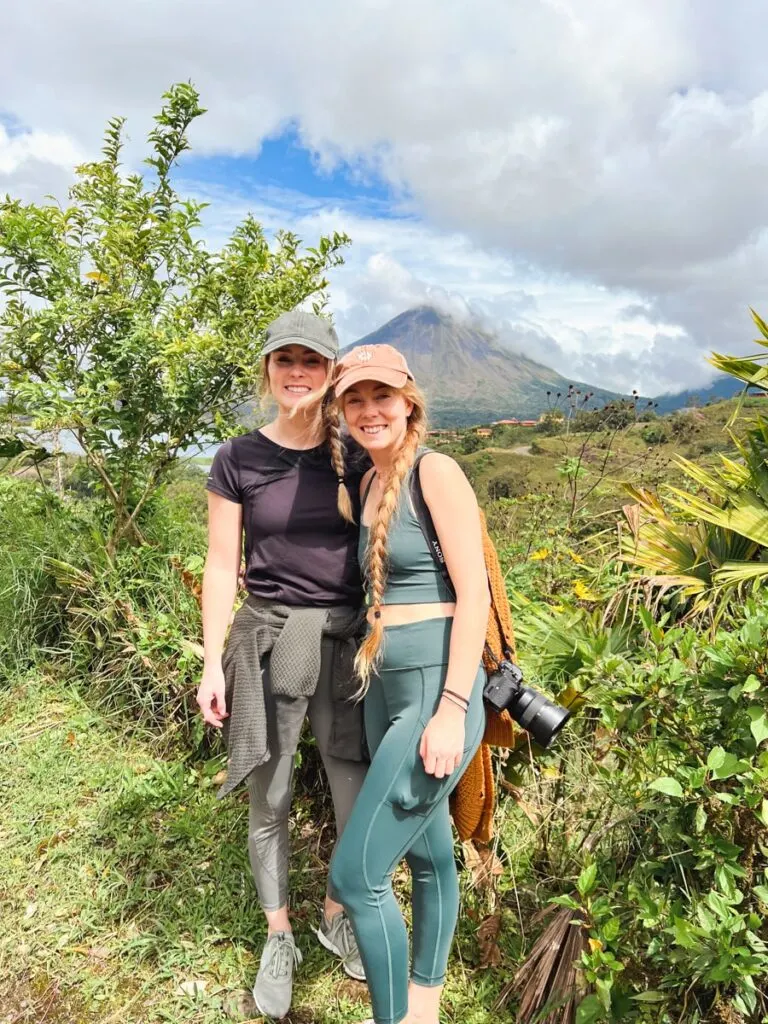 Laurin and Bri traveling in Costa Rica standing in front of La Fortuna Volcano
