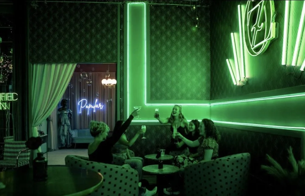 people toasting at fairlane hotel wicked inspired bar with green lighting 