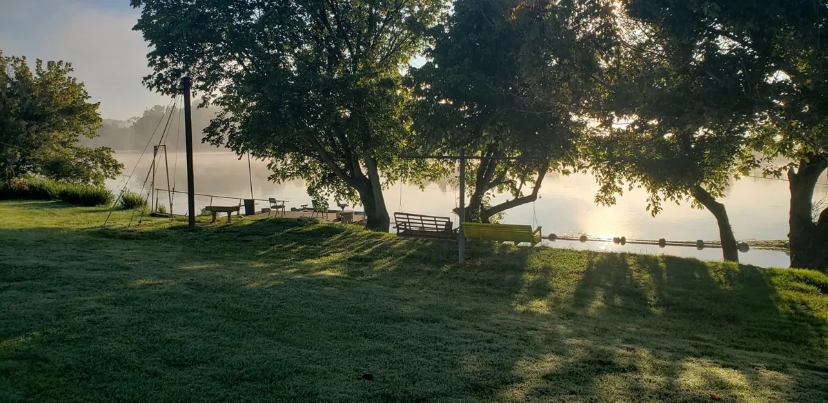 view of the river at sunset with grass and trees at windy rivers campground in rogersville tn 