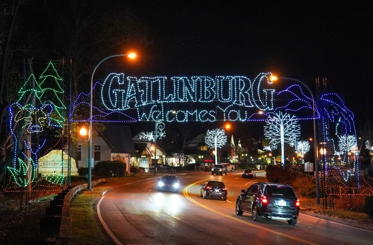 cars driving into gatlinburg with christmas lights saying "gatlinburg welcomes you"