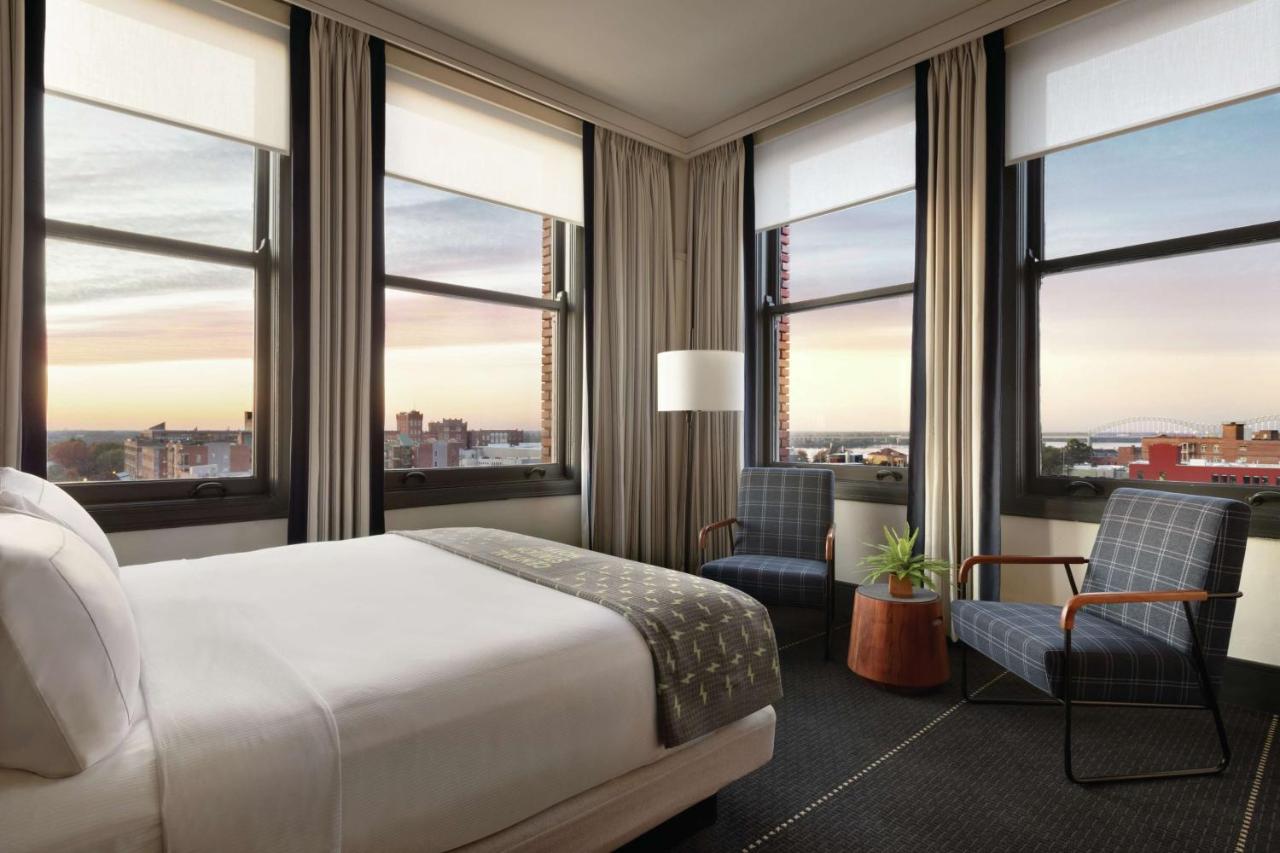 a room at the central station hotel in memphis overlooking the city with multiple windows and a queen bed