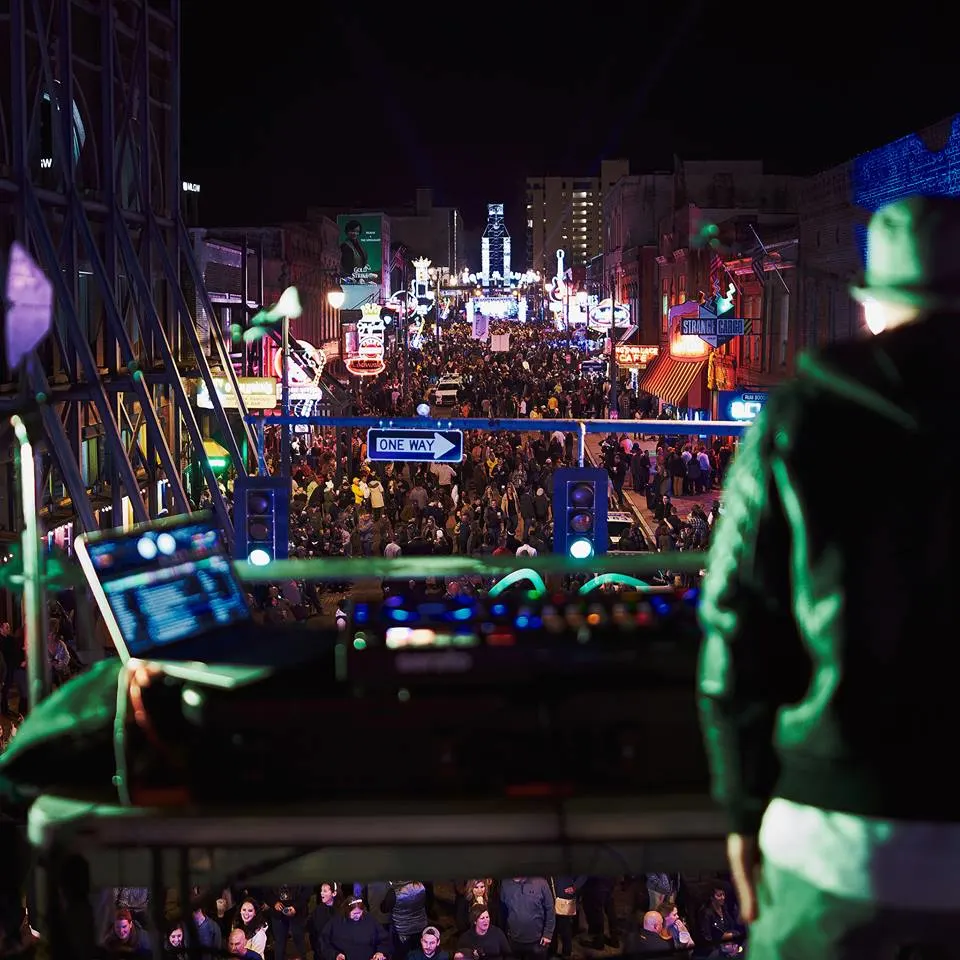 a crowd on beale street in downtown memphis celebrating the new year with a dj and fireworks