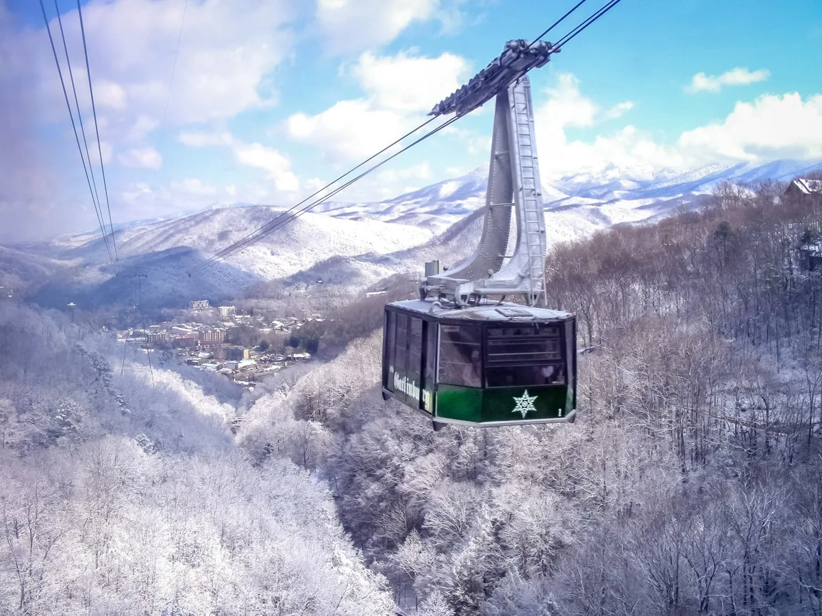 Aerial tram at ober Gatlinburg over snow-crested mountains and trees 