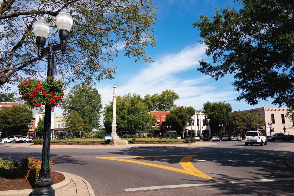 Downtown Franklin TN road with lamp post and flowers with statue in background and historic cannons