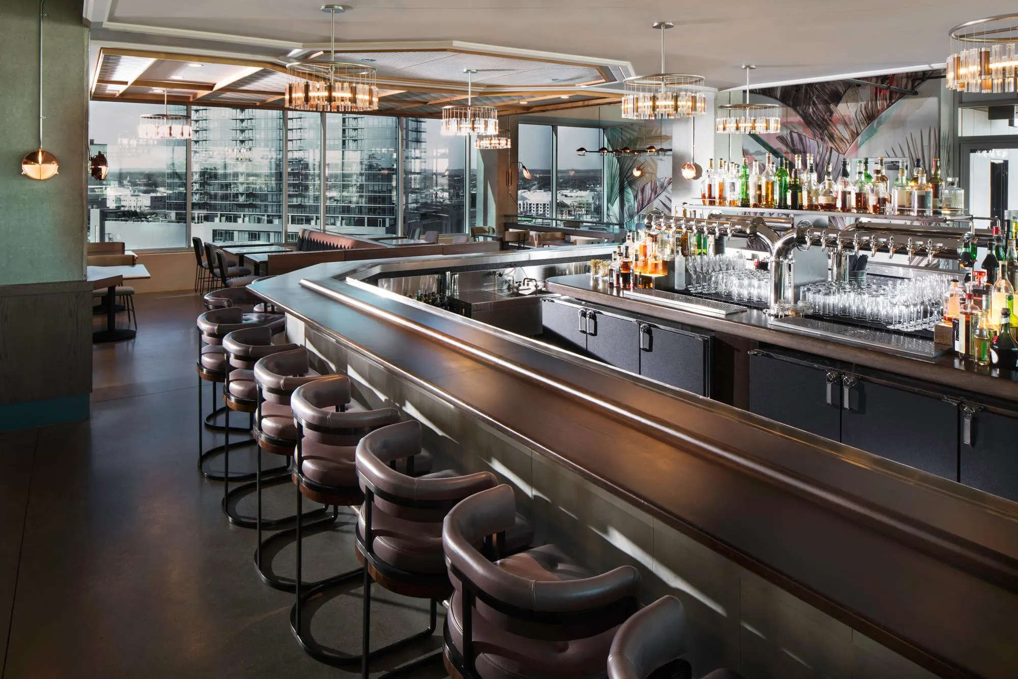 modern interior of the rooftop bar at L.A Jackson with bar and bar chairs with large windows ovrlooking nashville