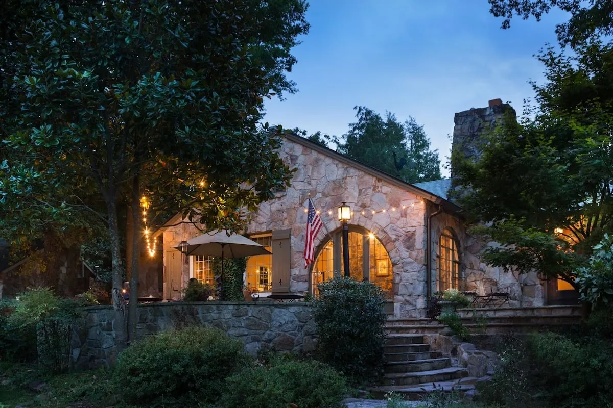 front view of the Chanticleer Bed and Breakfast at night in Chattanooga with stone siding, trees, and cozy lighting 
