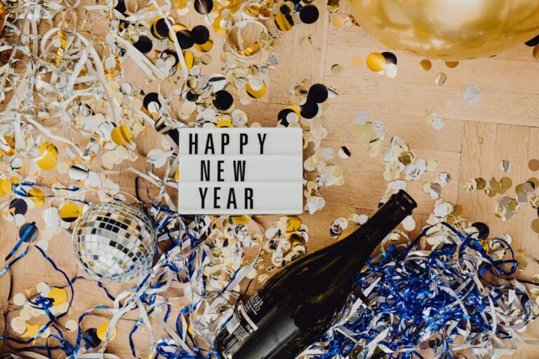 Happy New Year sign laying on confetti and a bottle of champagne for new years celebrations