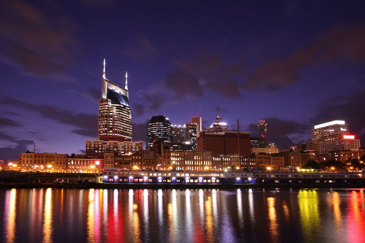 the nashville skyline at night with the reflection of the buildings on the water 