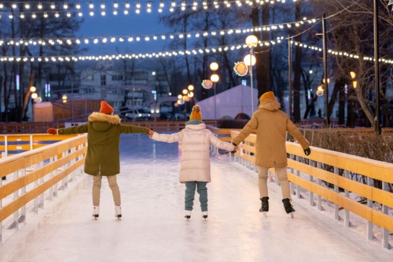 three people ice skating holding hands at night under twinkling lights